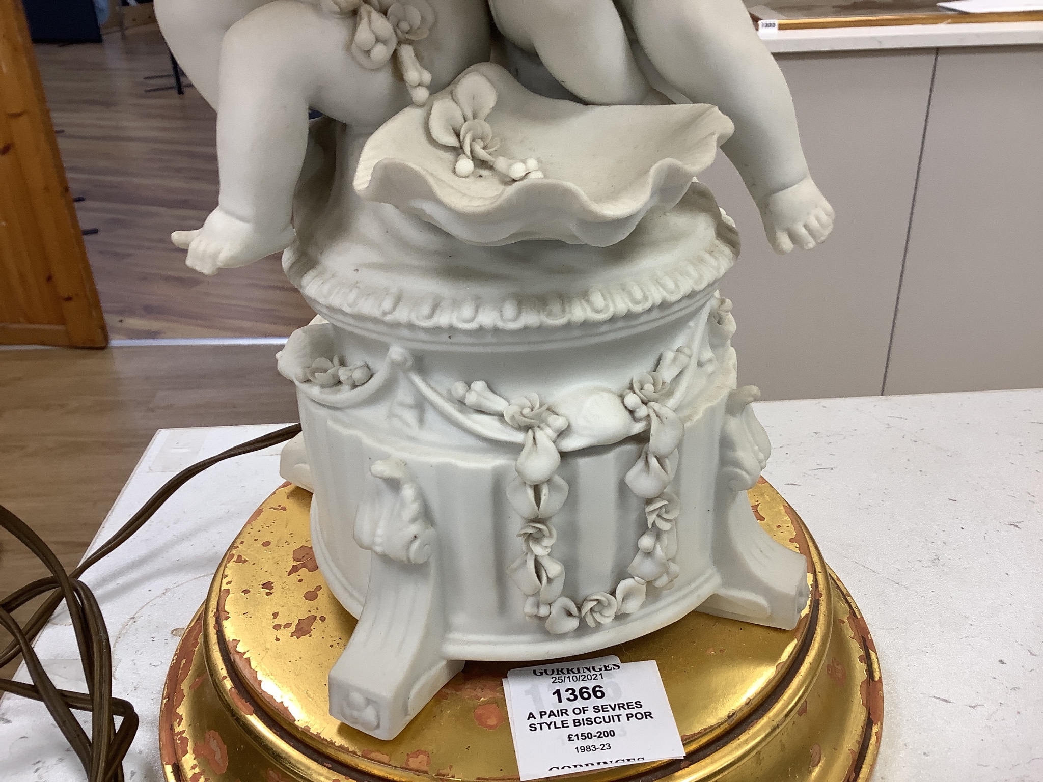 A pair of Sevres style biscuit porcelain groups of putti, fitted as a table lamps with shades 69cm total height incl shades